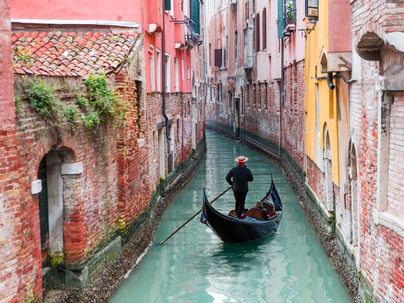 Venetian,Gondolier,Punting,Gondola,Through,Green,Canal,Waters,Of,Venice,